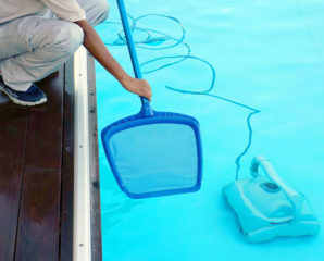A person cleaning and maintaining a pool with a net and pool cleaner